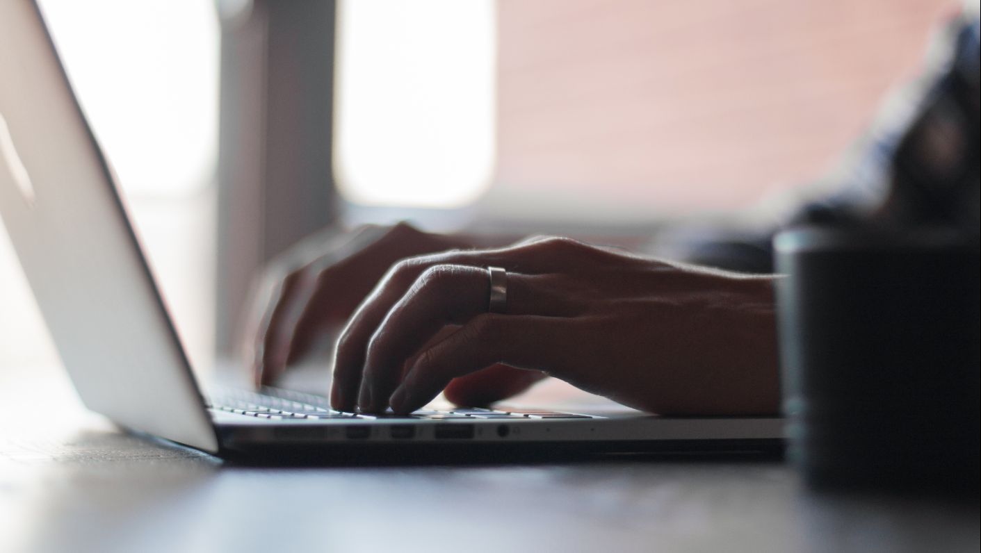 Hands typing on a laptop